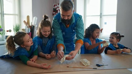 Group of little kids with teacher working with pottery clay during creative art and craft class at school.