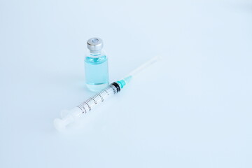 Vaccine bottle and syringe placed on a white table. Healthcare and medical concept.