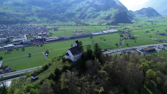 Old romanic chapel on a hill in beautiful swiss mountain panorama, aerial orbit