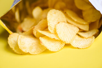 Potato chips on yellow background, Potato chips is snack in bag package wrapped in plastic ready to eat and fat food or junk food