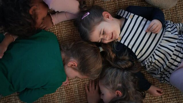 Top view of of tired little girls friends lying on back on floor and sleeping.