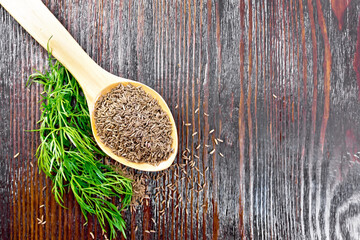Cumin seeds in spoon with herbs on board top