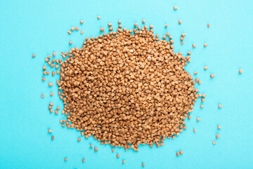 Buckwheat heap on blue background. Raw buckwheat on blue.