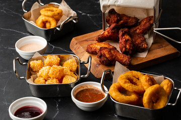 The beer plate with spicy chicken wings, calamari rings, fries onion rings, cheese balls, potatoes, breaded.