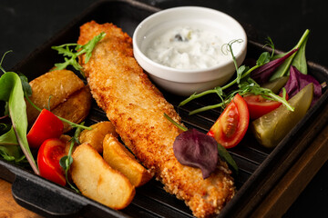 One piece of baked salmon grilled lemon and salt on a dark plate with potatoes. marble background
