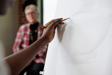 Close up of creative student sketching vase model on canvas working at graphic illustration using sketch pencil during art course. Painter man learning drawing technique. New years resolutions