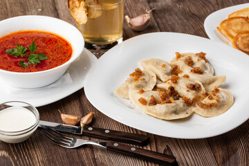 Traditional ukrainian dish vareniki and borscht served with greaves and sour cream. Close up view of traditional Ukrainian food.