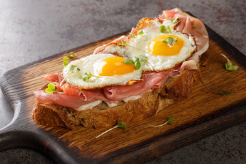 Strammer Max is a German open faced sandwich with ham and eggs closeup on the wooden board on the table. Horizontal - obrazy, fototapety, plakaty