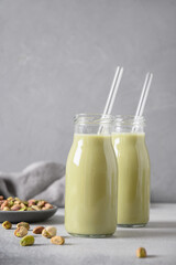 Pistachio milk in bottles on gray background. Lactose free. Vegan nutty plant based milk. Vertical format.