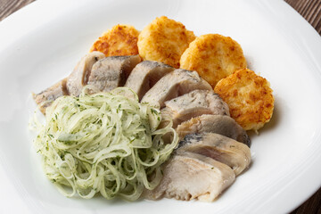 Herring with potatoes and onions on a plate. Ukrainian traditional cuisine on wooden background.