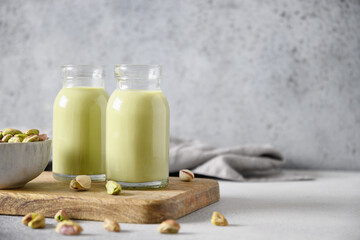 Pistachio milk in in bottles on gray background. Horizontal orientation. Lactose free. Vegan nutty plant based milk. Copy space.