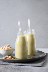 Pistachio milk in bottles on gray background. Lactose free. Vegan nutty plant based milk. Vertical. Lack of cholesterol.