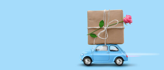 Blue toy car with gift box and rose flower atop.