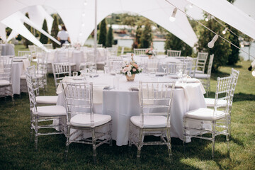 banquet table setting under a white tent on the grass