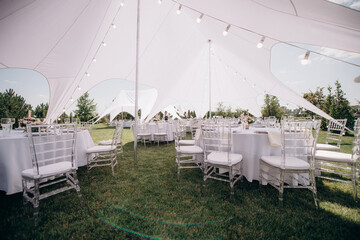 banquet table setting under a white tent on the grass