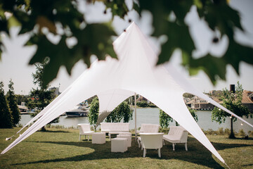 banquet table setting under a white tent on the grass