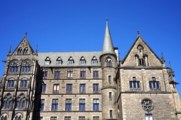 Fassade mit altem Mauerwerk der Alten Universität vor blauem Himmel im Sonnenschein in der Altstadt von Marburg an der Lahn in Hessen