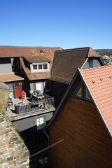 Alte Dächer mit Mansarde, Dachgaube Spitzgiebel und Dachterrasse vor blauem Himmel im Sonnenschein...