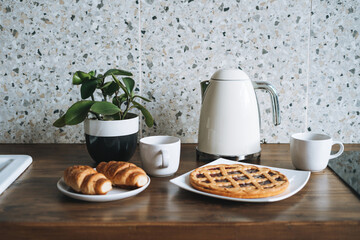 Work surface table with pastries and kettle in kitchen at home