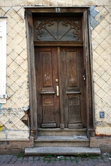 Schiefe alter Haustür aus braunem Holz eines Altbau in Beige und Naturfarben in den Gassen der...