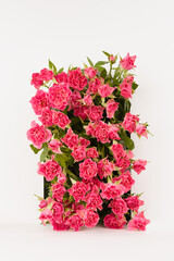 Elegant rectangle arch of fresh little roses - abstract podium on white stage for presentation cosmetic products, mockup, vertical. Flowers template for wedding invitation, advertising, design.