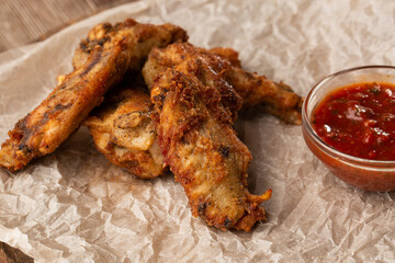 Fried Chicken Wings Covered in True Hot BBQ Sauce served with red hot chilli sauce on a parchment...