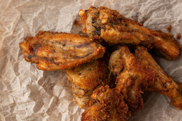 Fried Chicken Wings Covered in True Hot BBQ Sauce served with red hot chilli sauce on a parchment paper on wooden background.