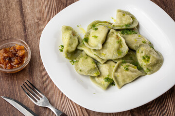 Traditional ukrainian dish vareniki served in a bowl with greaves and basil sauce. Close up view of traditional Ukrainian food.