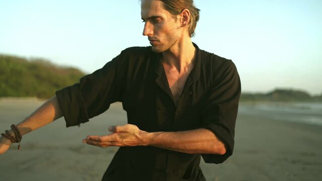 millennial young fit man practice Qi gong,  Tai Chi yoga on beach, summer. outdoor activities, social distancing.