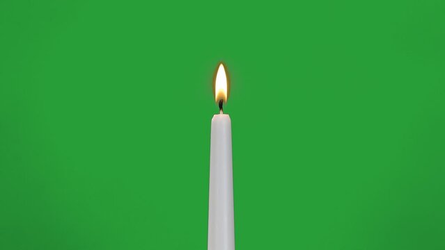 white candle burns on green screen