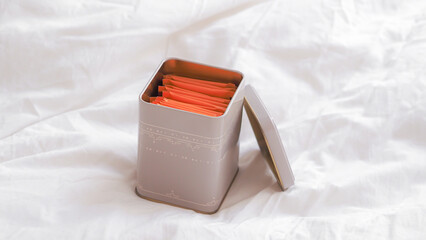 Orange tea bags in a box on a white crumpled sheet