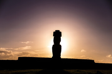 Scenic view of an antique Moai stone statue silhouette on Easter Island, Chile against cloudy sunset