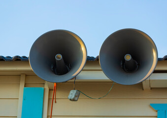 Pair of big retro loudspeakers the roof outside against blue sky. Urgent or emergency announcement...