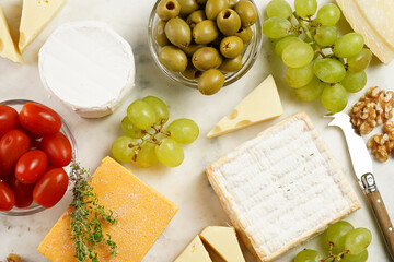 Cheese platter with organic cheeses - blue cheese cheddar, emmantaler, french soft cheese with strong smell, italian parmesan, grapes, tomatoes, olives, nuts and crackers on marble board