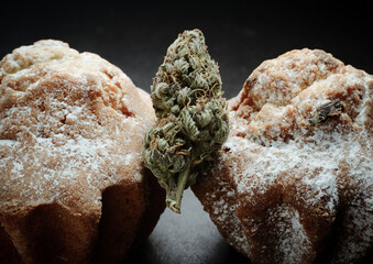 Marijuana Sweets. Canna Kitchen, cooked with Cannabis. Cupcakes with marijuana buds, macro view. Weed cakes with CBD oil and cannabis blooms on black background.