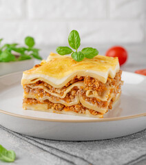 Slice of Lasagna bolognese with meat sauce and bechamel with melted cheese on top and fresh basil. Italian cusine. Copy space.