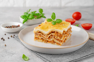 Slice of Lasagna bolognese with meat sauce and bechamel with melted cheese on top and fresh basil. Italian cusine. Copy space.