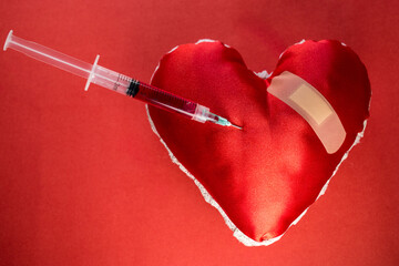 Background of blood donation theme with a syringe with blood in a heart shaped object