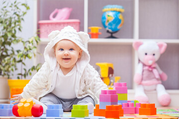 baby girl playing with colourful building blocks at home or kindergarten