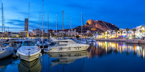 Alicante Port d'Alacant marina with boats and view of castle Castillo twilight travel traveling holidays vacation panorama in Spain - obrazy, fototapety, plakaty