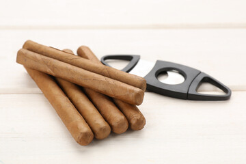 Cigars and guillotine cutter on white wooden table