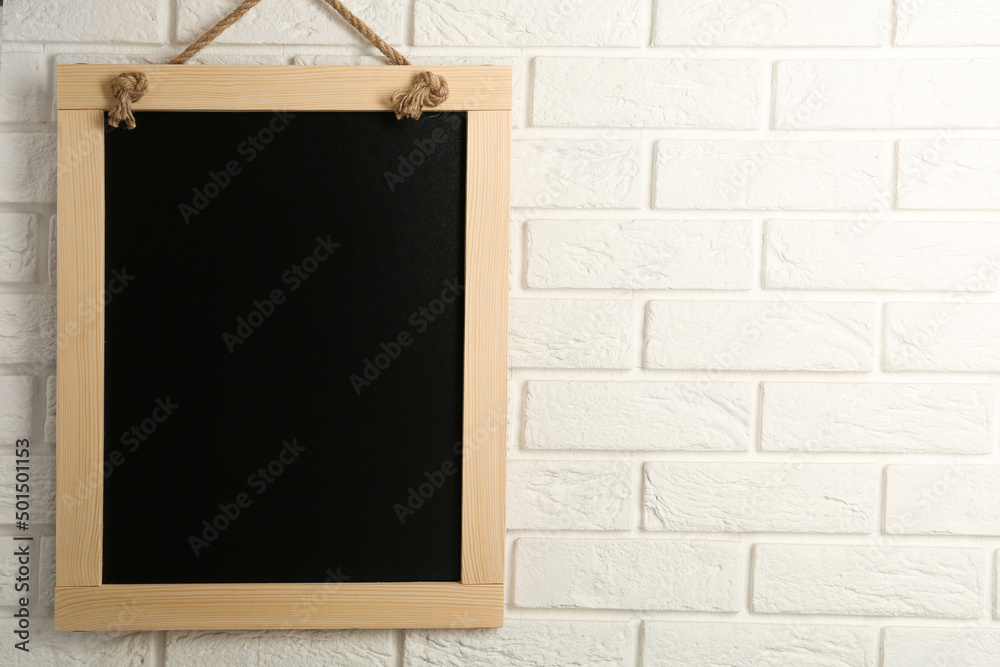 Sticker Clean small black chalkboard hanging on white brick wall, space for text