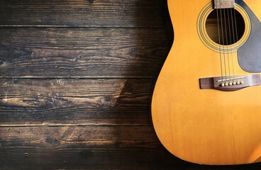 Obraz premium Acoustic guitar on wooden floor, soft light and shadow.