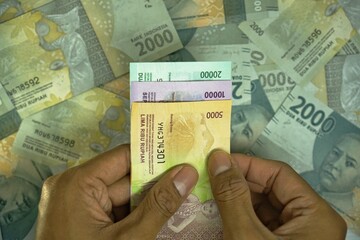 5000, 10000, 20000 IDR, Indonesian Rupiah money concept was held by businessman on money background