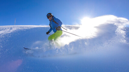 A skier going down the slope in Goldeck, Austria. Perfectly groomed slopes. The crispy snow is...