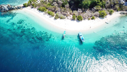 A drone shot of a paradise island with some boats anchored around in Komodo National Park, Flores,...