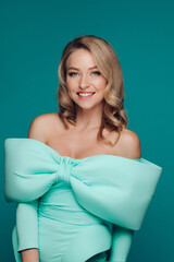 Beautiful elegant woman in a bright tiffany dress with a bow on her chest in the studio on a...