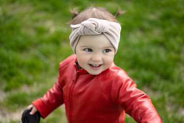 Portrait of a 2 year old girl. Girl in a red leather jacket and headband.