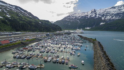 Aerial shot of the Whittier port in Alaska with a cruise ship approaching from between two mountains