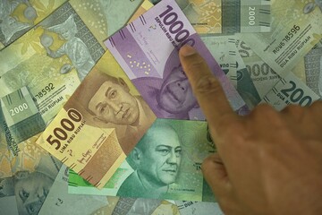 5000, 10000, 20000 IDR, Indonesian Rupiah money concept was held by businessman on money background
